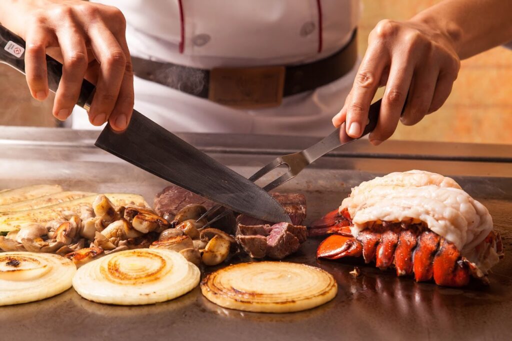A chef is preparing food on a grill.