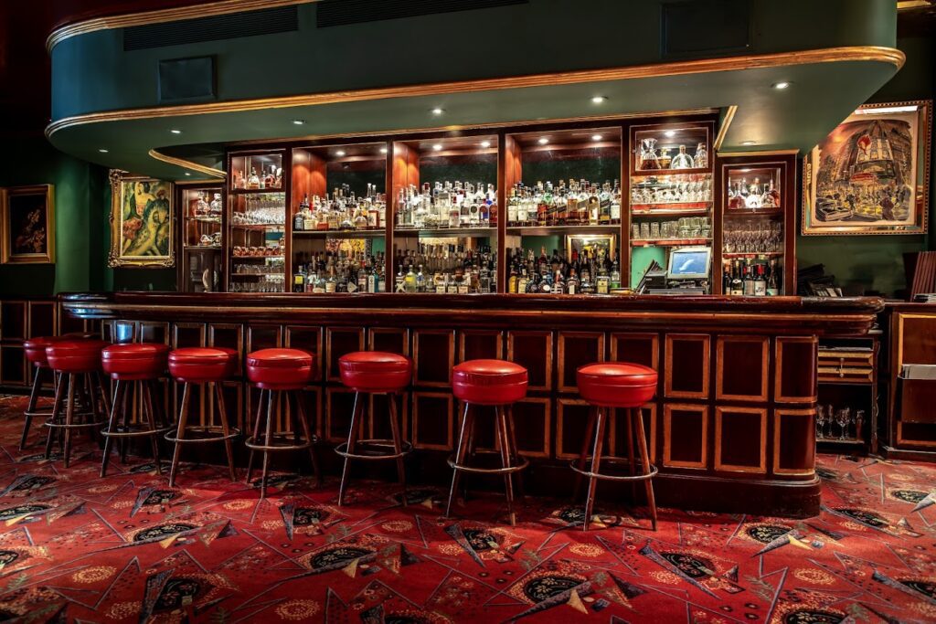A bar with red stools and a red carpet.
