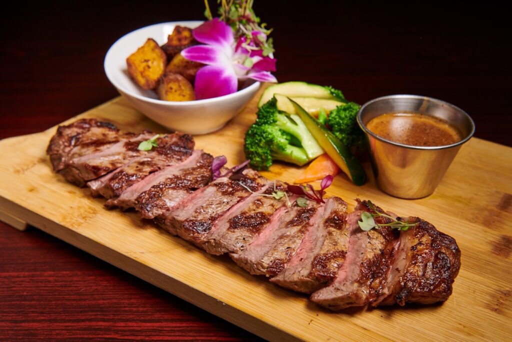 A steak is sitting on a wooden cutting board.