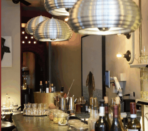 Cozy bar with hanging lanterns and neatly arranged bottles.